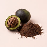Black walnut in its green-black hull with dark hull powder on blush-oat