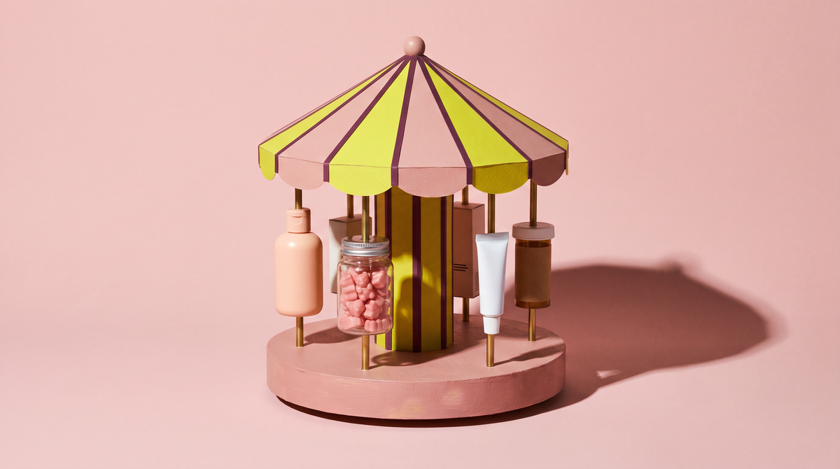 A handmade miniature carousel with a pink and yellow-green canopy on blush; its riders are generic, unbranded wellness products on brass poles